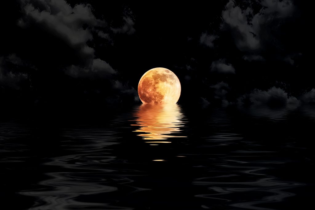 dark red full moon in cloud with water reflection closeup showing the details of the lunar eclipse